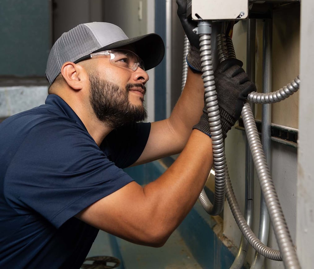 HVAC maintenance technician in navy polo shirt and TDIndustries hat