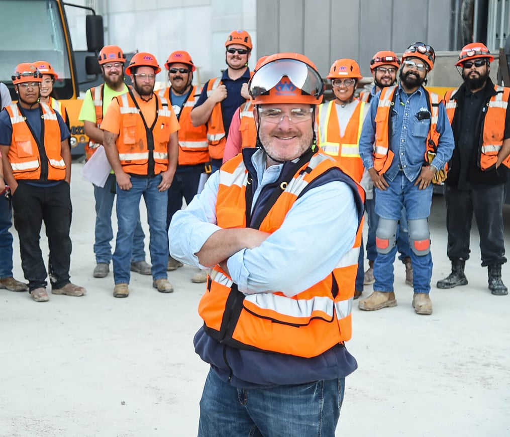 Construction leader poses with team during job site safety meeting